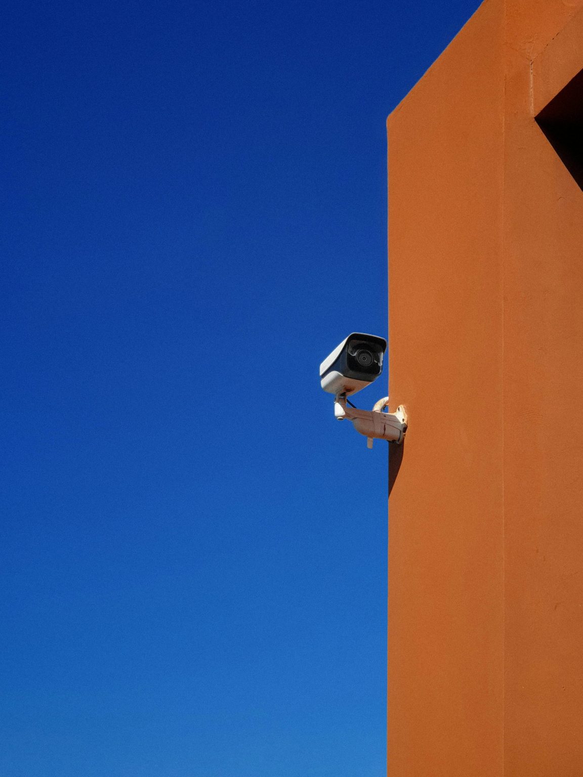 security camera against sky and orange wall